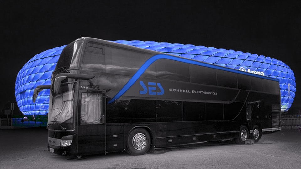 Ein großer Eventbus wird vor einer beleuchteten Arena bei Nacht geparkt gezeigt. Die Busseite wird mit dem Firmenlogo und dem Schriftzug „Schnell Event-Services“ beschriftet.


